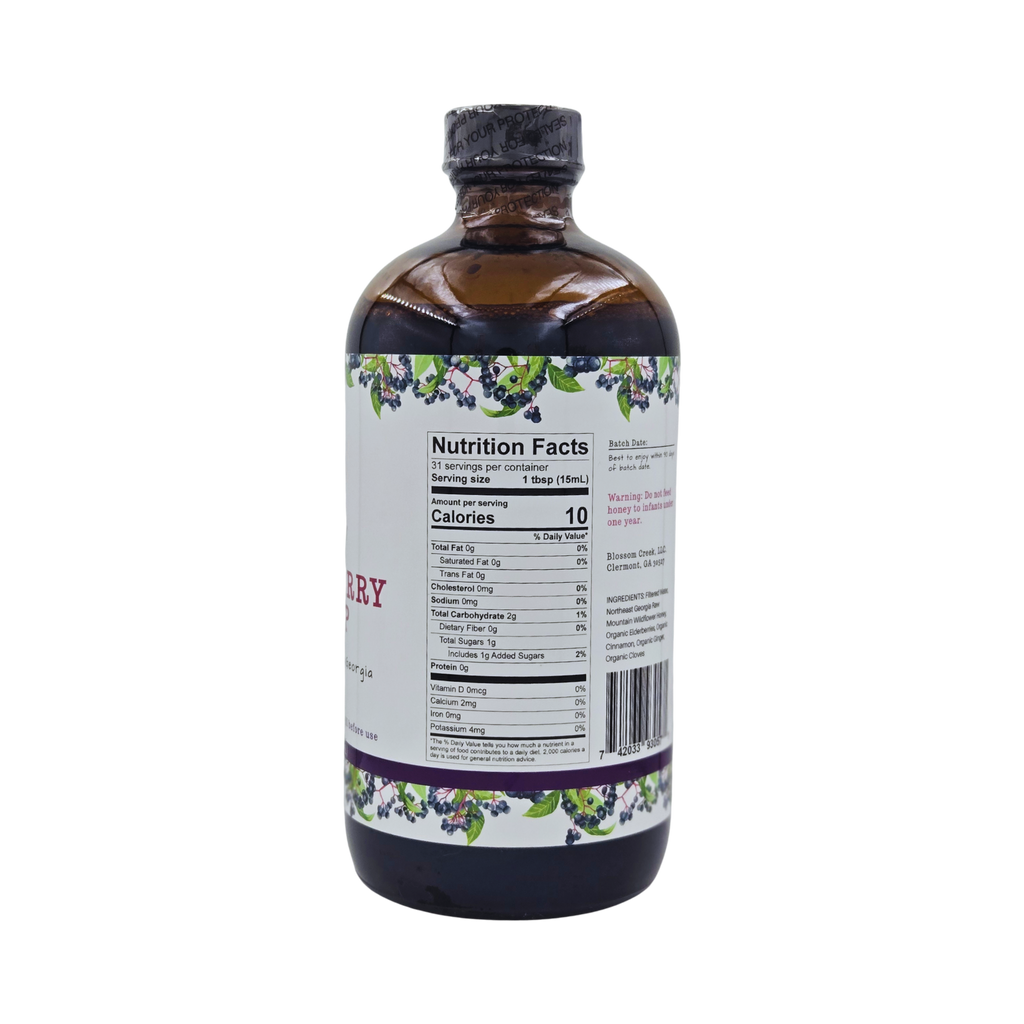 Side view of Blossom Creek 16 oz Elderberry Syrup in an amber glass bottle, featuring the white label with purple and green elderberry illustrations and Nutrition Facts panel.