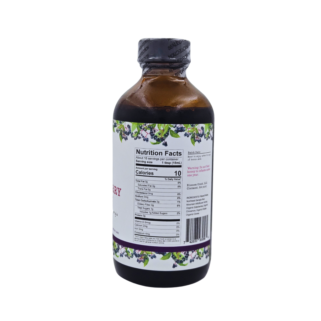 Side view of Blossom Creek 8 oz Elderberry Syrup in an amber glass bottle, featuring a white label with purple and green elderberry illustrations and the Nutrition Facts panel.